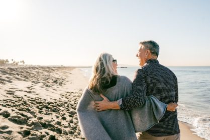 Un couple de seniors regarde la mer depuis une plage.